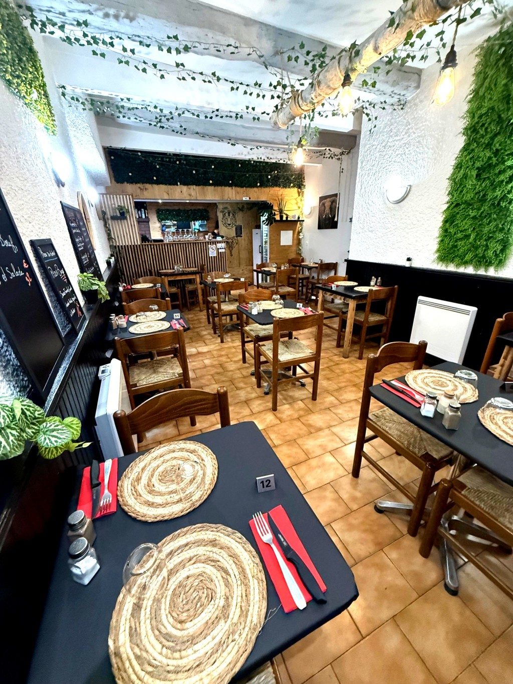 La salle : tables en bois, plantes vertes et décoration naturelle